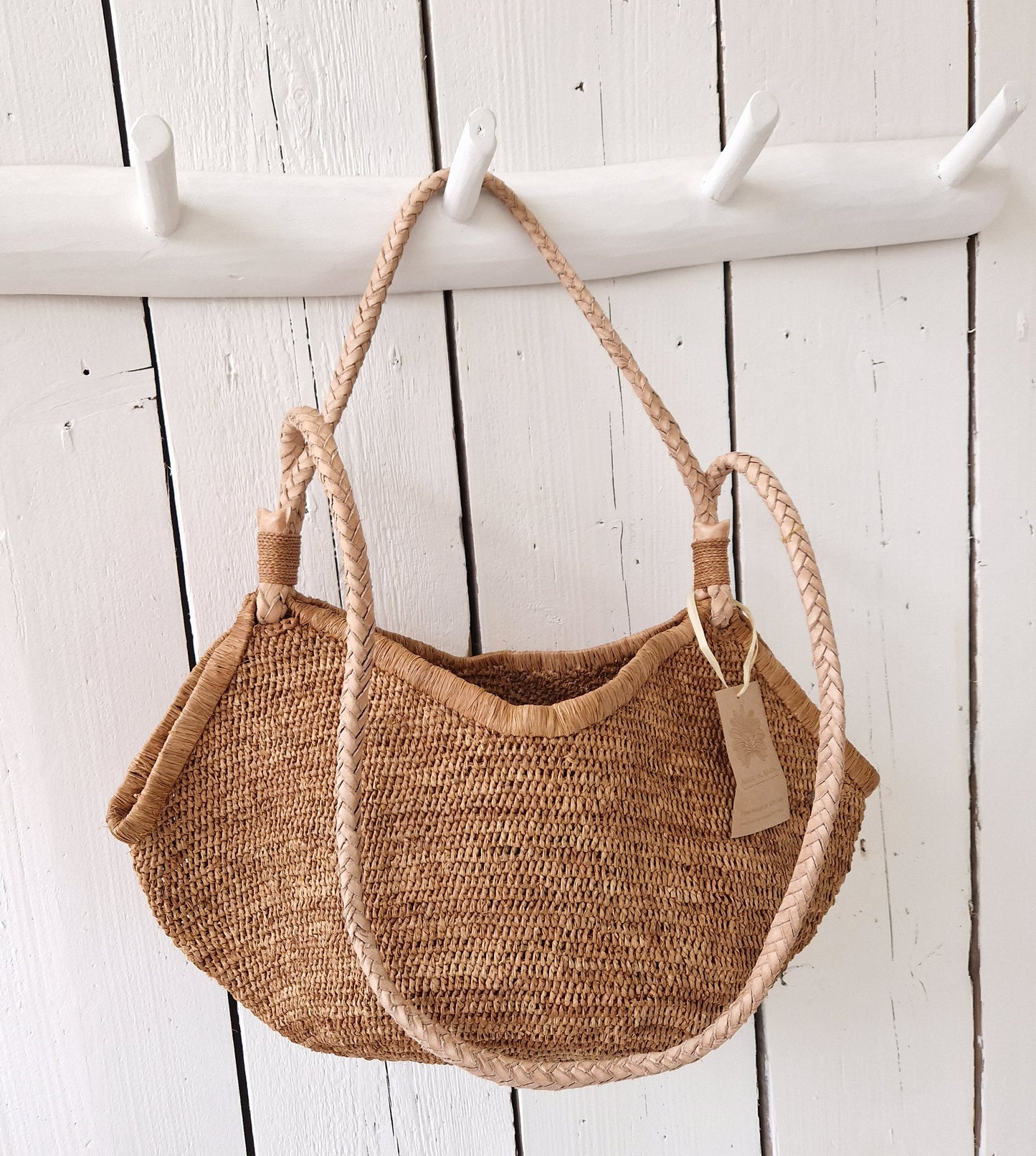 Aina M Bag Light Brown van Made in Mada hangend aan witte kapstok, met mooie ronde schelpvorm