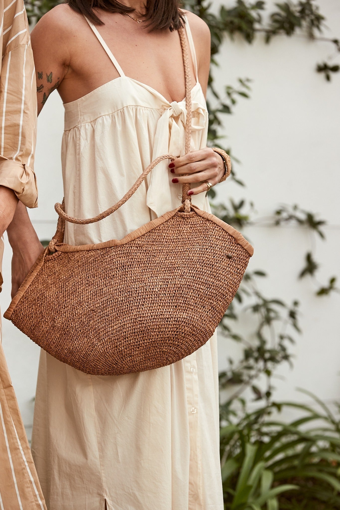 Aina M Bag Light Brown van Made in Mada gedragen bij een lichte zomerjurk, handgeweven en elegant