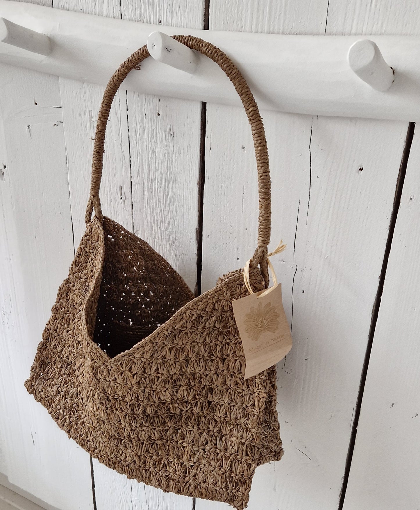 Valiha Bag van Made in Mada aan witte houten haak, handgeweven raffia tas.