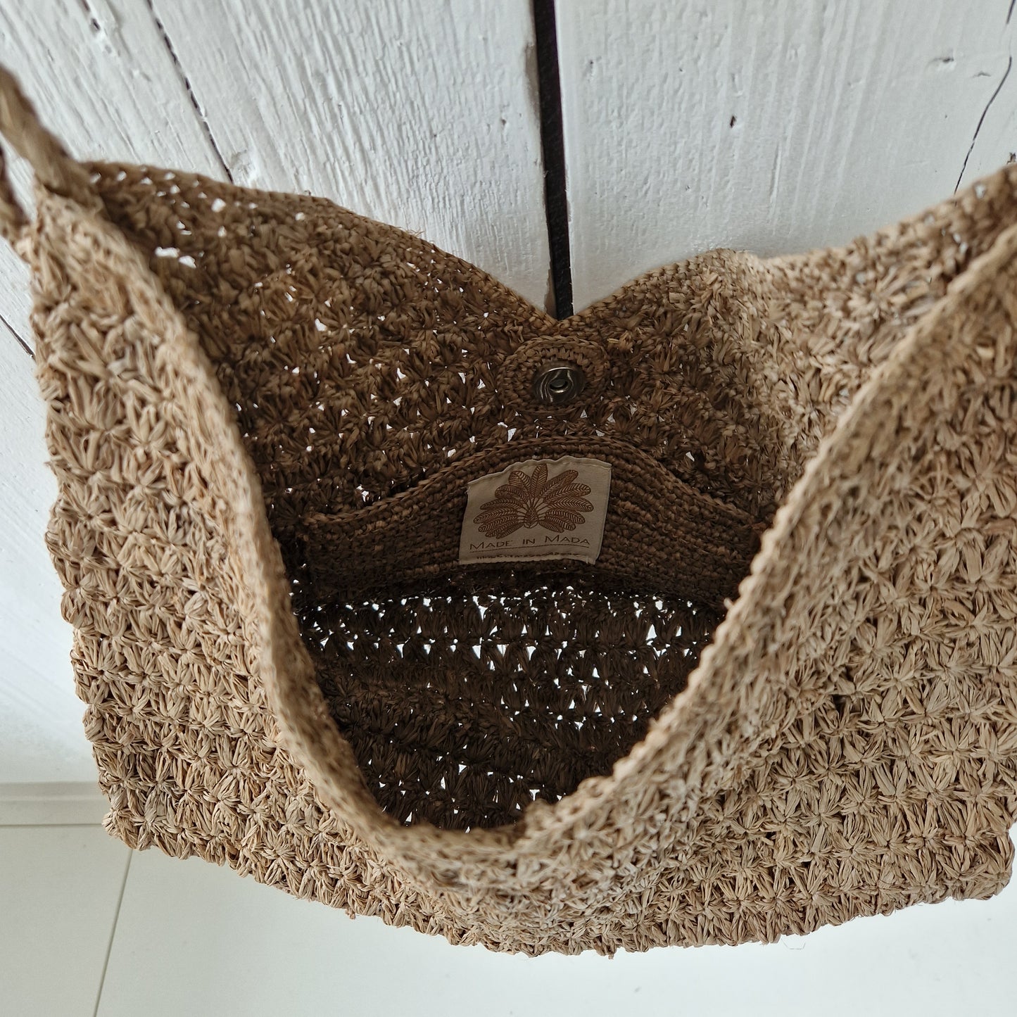 Binnenkant van de Valiha Bag van Made in Mada met zichtbare magneetsluiting en label, handgeweven raffia met open structuur
