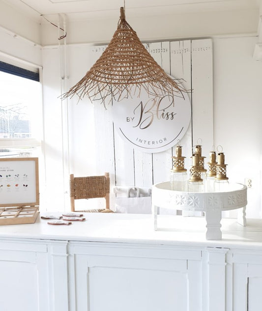 Wit interieur met witte chakki tafel met goudkleurige marokkaanse jampot lantaarns. En een dadel hanglamp daarboven.