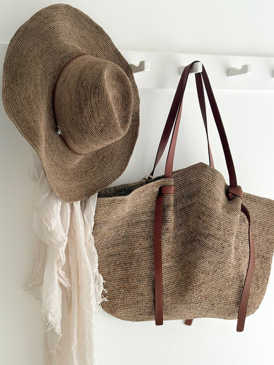 Grote raffia tas Gemma XL tan leather in tea kleur aan kapstok met de Aziz hat tan leather van Made in Mada