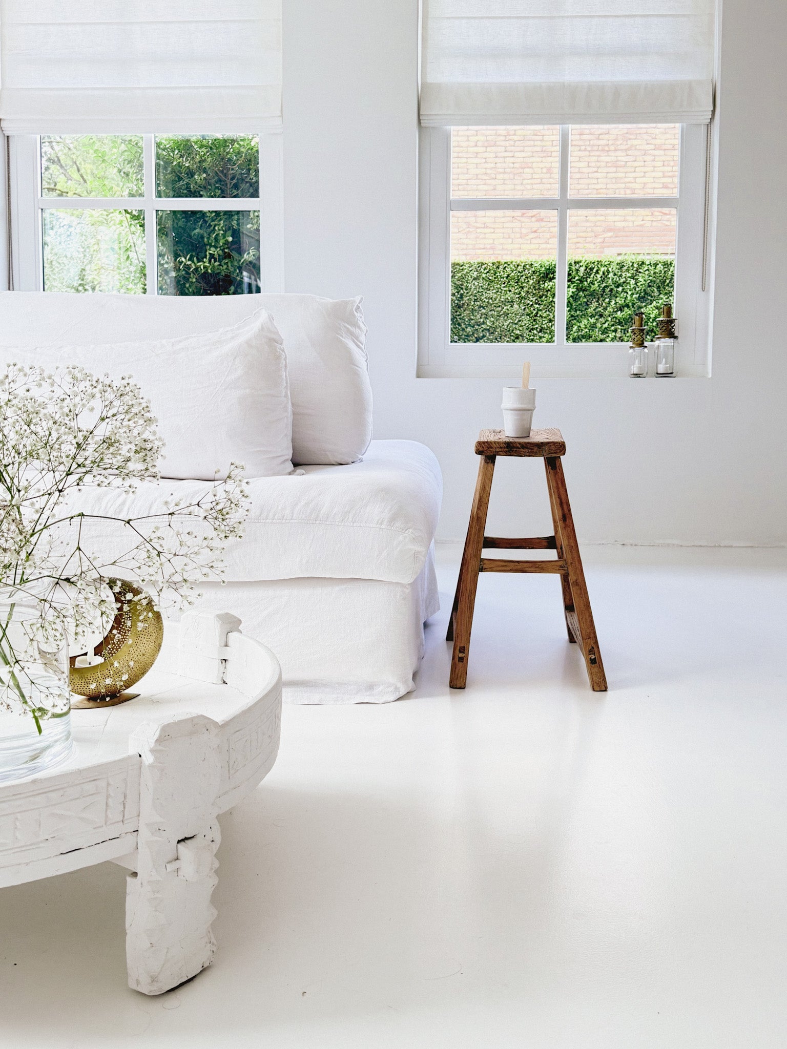 Oude Chinese kruk naast witte bank in wit interieur