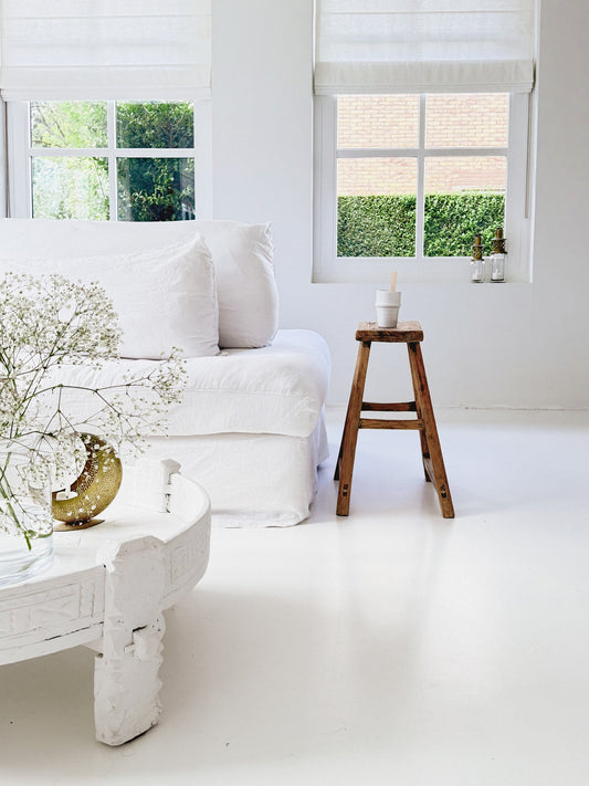 Oude Chinese kruk naast witte bank in wit interieur