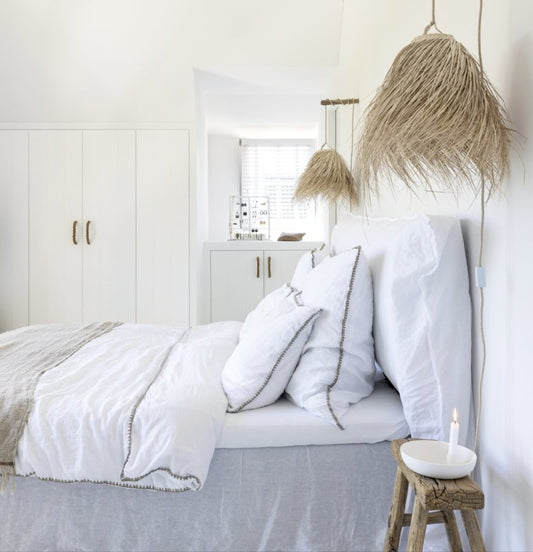 Palmleaf hanglampen Cloche small aan weerszijden van een bed met wit linnen beddengoed